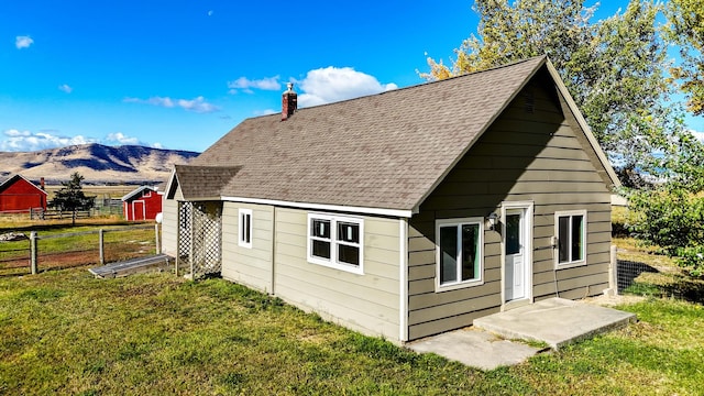 back of property with a mountain view and a lawn