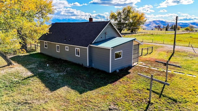 view of property exterior featuring an outdoor structure, a mountain view, and a lawn