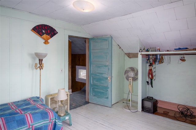 interior space featuring wood walls, hardwood / wood-style flooring, and vaulted ceiling