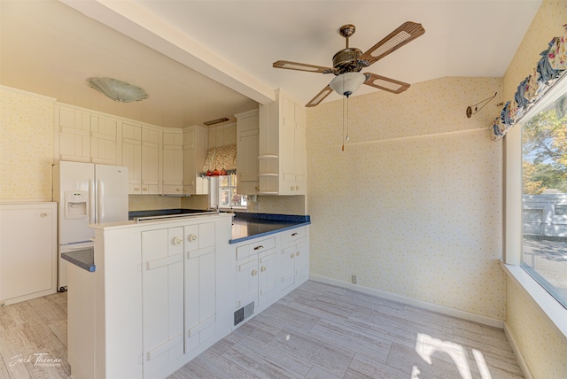 kitchen featuring white cabinetry, white fridge with ice dispenser, a wealth of natural light, and kitchen peninsula