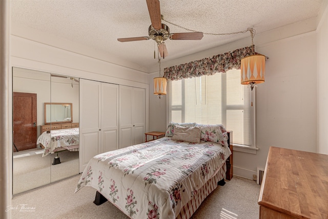 bedroom featuring a closet, a textured ceiling, light colored carpet, and ceiling fan