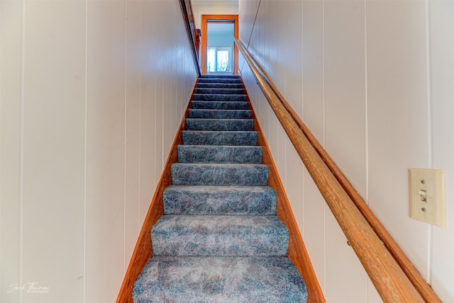 staircase featuring wooden walls