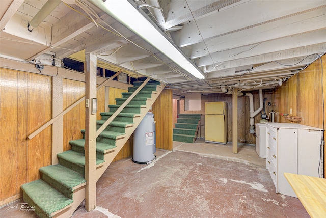 basement featuring wood walls, electric water heater, and white refrigerator