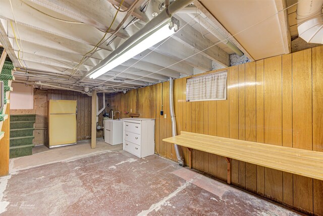 basement featuring white fridge and wood walls