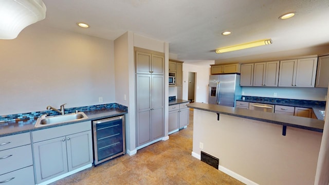 kitchen featuring appliances with stainless steel finishes, sink, a kitchen bar, and beverage cooler