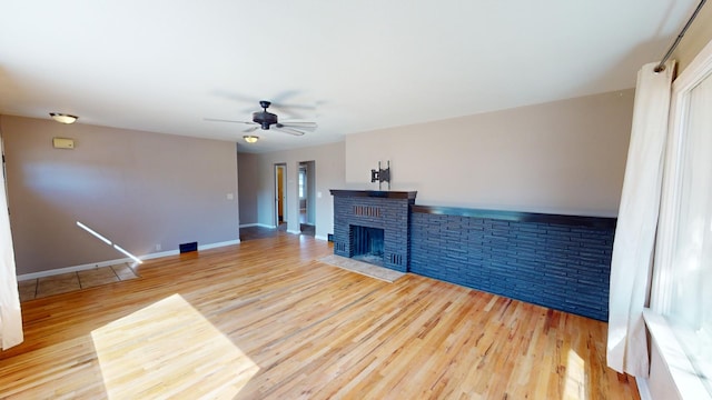 unfurnished living room with hardwood / wood-style flooring, ceiling fan, and a brick fireplace