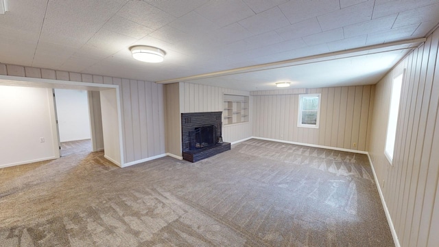 unfurnished living room featuring wooden walls, carpet flooring, and a brick fireplace