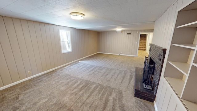 unfurnished living room featuring light colored carpet, a fireplace, and wooden walls