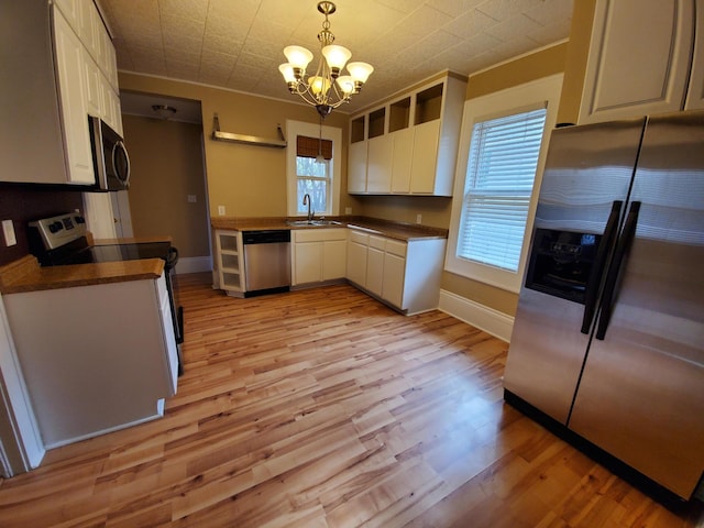 kitchen featuring a wealth of natural light, appliances with stainless steel finishes, hanging light fixtures, and light hardwood / wood-style flooring