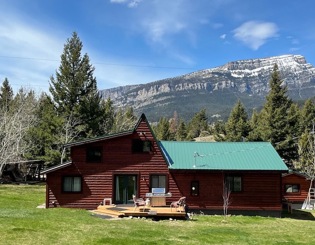 back of property with a yard and a deck with mountain view