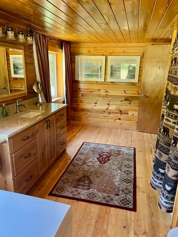 bathroom featuring vanity, wood ceiling, hardwood / wood-style flooring, and wooden walls