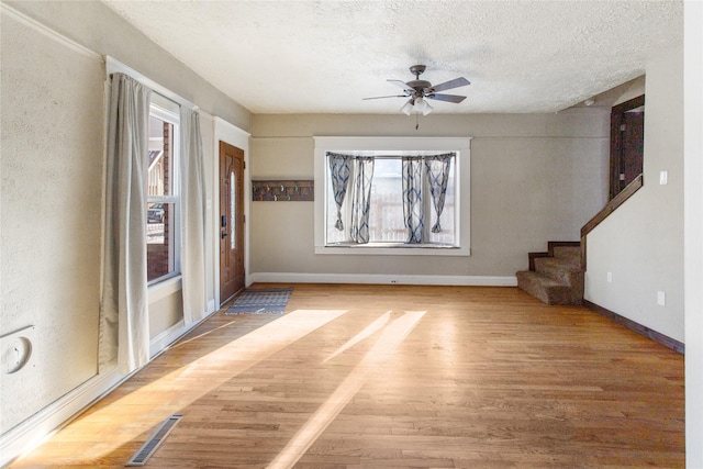 unfurnished living room featuring ceiling fan, wood-type flooring, and a textured ceiling