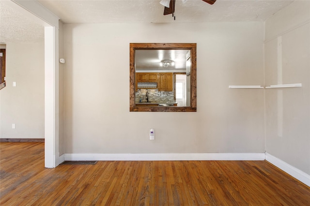 unfurnished room with ceiling fan, hardwood / wood-style flooring, and a textured ceiling