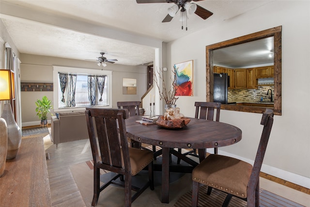 dining room featuring ceiling fan, sink, light hardwood / wood-style flooring, and a textured ceiling