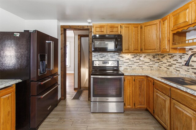 kitchen featuring high end fridge, sink, backsplash, and stainless steel electric range