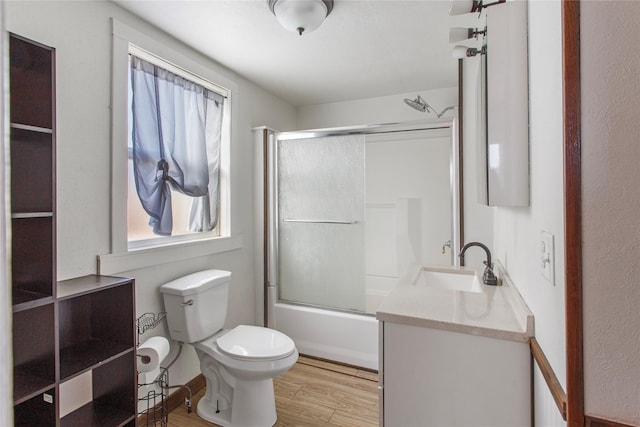 full bathroom featuring enclosed tub / shower combo, vanity, hardwood / wood-style floors, and toilet