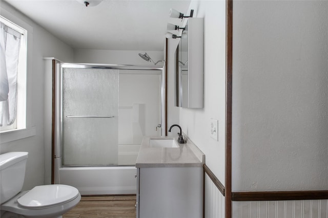 full bathroom with enclosed tub / shower combo, hardwood / wood-style floors, vanity, and toilet