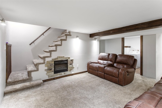 carpeted living room with beamed ceiling, washer / clothes dryer, and a stone fireplace