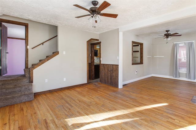 unfurnished living room featuring ceiling fan, light hardwood / wood-style floors, and a textured ceiling