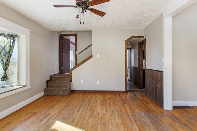 unfurnished living room with ceiling fan, a textured ceiling, and light wood-type flooring