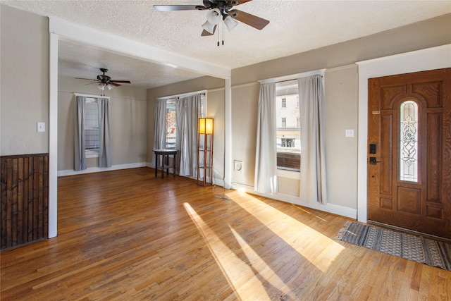 foyer featuring ceiling fan, wood-type flooring, and a textured ceiling