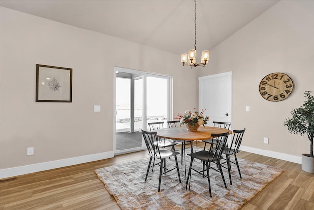 dining room featuring light wood-type flooring, high vaulted ceiling, and an inviting chandelier