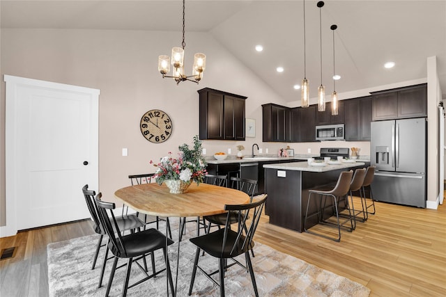 kitchen featuring pendant lighting, lofted ceiling, appliances with stainless steel finishes, a kitchen island, and a breakfast bar area