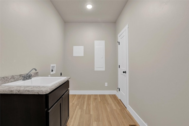 laundry room with cabinets, hookup for a washing machine, light wood-type flooring, electric dryer hookup, and sink