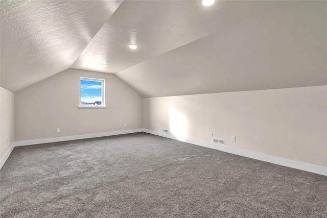 bonus room with lofted ceiling, carpet floors, and a textured ceiling