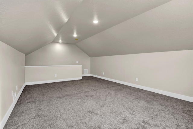 additional living space featuring carpet, lofted ceiling, and a textured ceiling