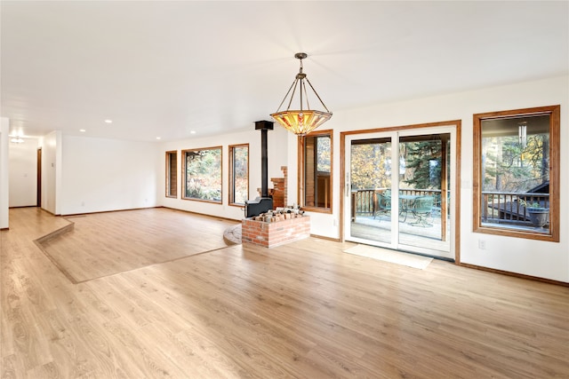 unfurnished living room featuring a wood stove and light wood-type flooring