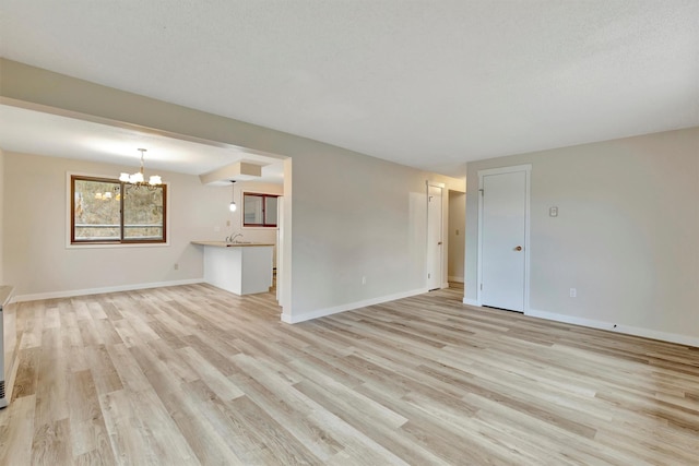 20622 US Highway 10 E, Clinton, MT 59825 - unfurnished living room with light wood-style flooring and a chandelier