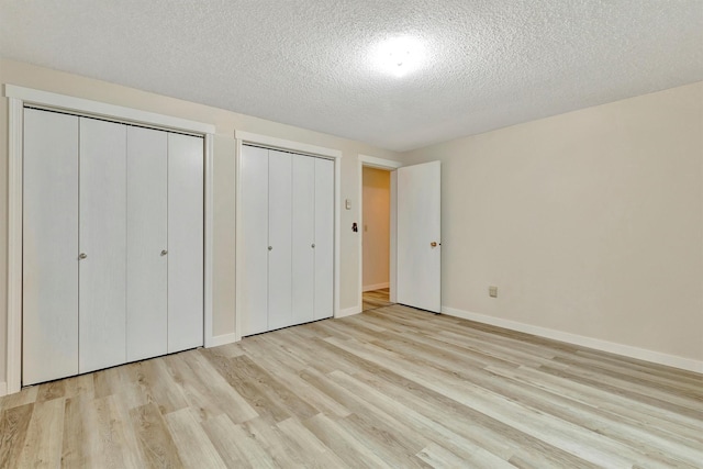 20622 US Highway 10 E, Clinton, MT 59825 - unfurnished bedroom featuring multiple closets, wood finished floors, and a textured ceiling