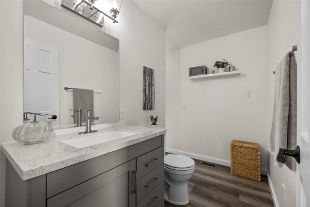 bathroom with vanity, toilet, and hardwood / wood-style flooring