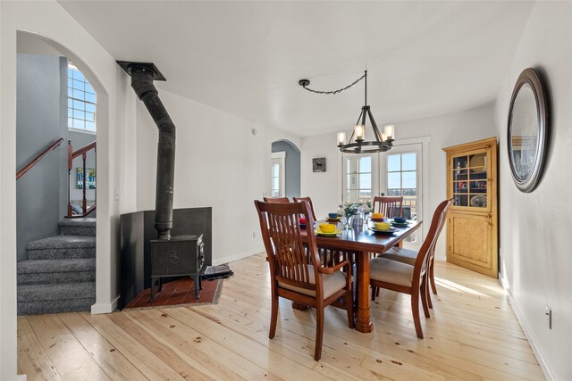 dining space featuring light hardwood / wood-style floors, a wood stove, and a notable chandelier