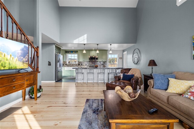 living room with light hardwood / wood-style floors and a towering ceiling