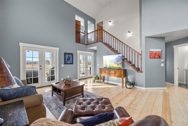 living room featuring french doors, light hardwood / wood-style floors, and high vaulted ceiling