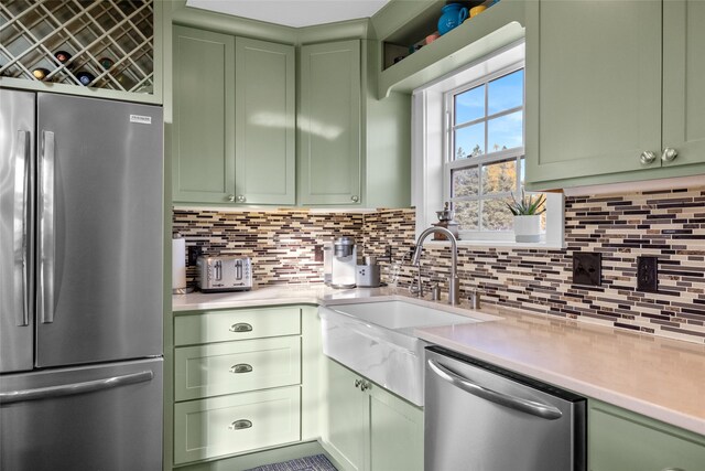 kitchen with green cabinets, stainless steel appliances, sink, and backsplash