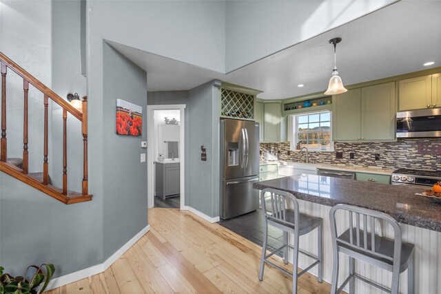 kitchen with pendant lighting, light hardwood / wood-style flooring, stainless steel appliances, and green cabinets