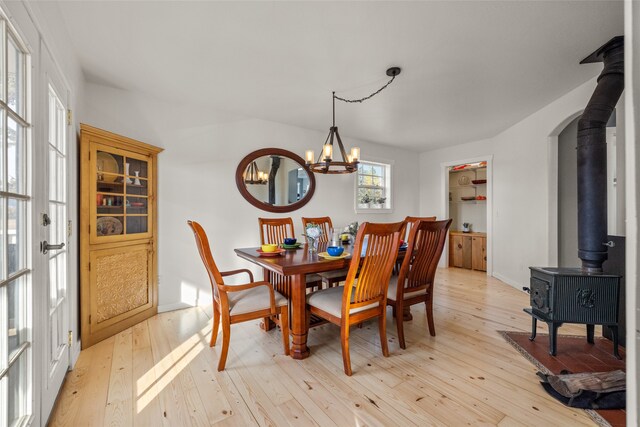 dining area with a chandelier, light hardwood / wood-style floors, and a wood stove