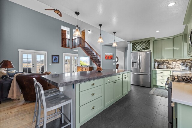 kitchen with green cabinetry, french doors, stainless steel appliances, pendant lighting, and a breakfast bar area