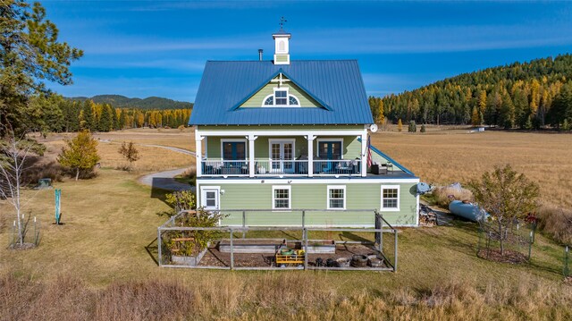 back of property with a balcony and a lawn