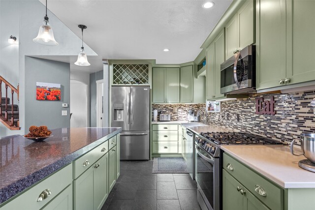 kitchen with appliances with stainless steel finishes, sink, green cabinets, decorative light fixtures, and decorative backsplash