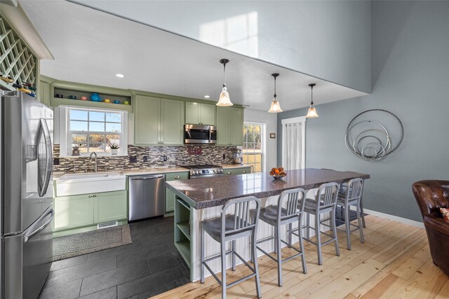 kitchen featuring light hardwood / wood-style floors, stainless steel appliances, green cabinetry, and a kitchen island