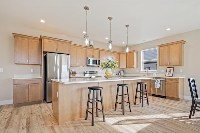 kitchen featuring sink, a kitchen island, a kitchen breakfast bar, light hardwood / wood-style floors, and stainless steel appliances