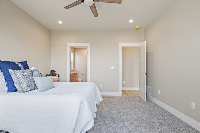 bedroom featuring light carpet, ensuite bathroom, and ceiling fan