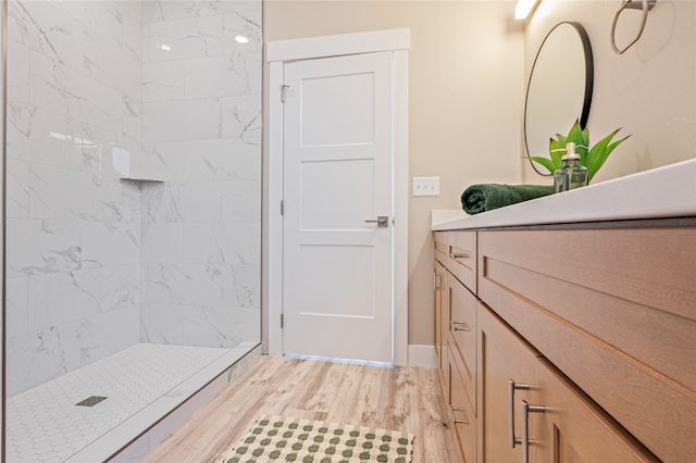 bathroom featuring vanity, a tile shower, and hardwood / wood-style flooring