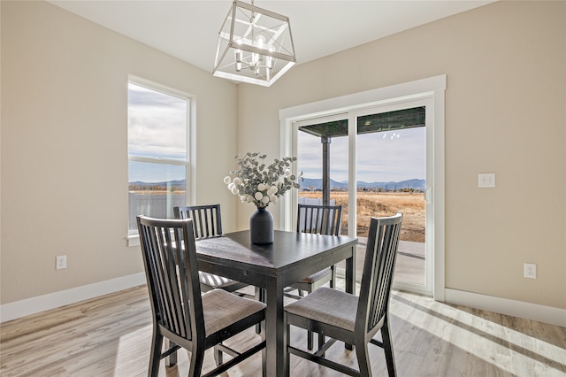 dining room with a mountain view, an inviting chandelier, and light hardwood / wood-style floors