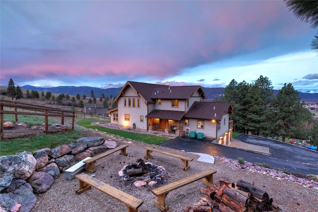 back house at dusk featuring a patio area, a mountain view, a fire pit, and a garage