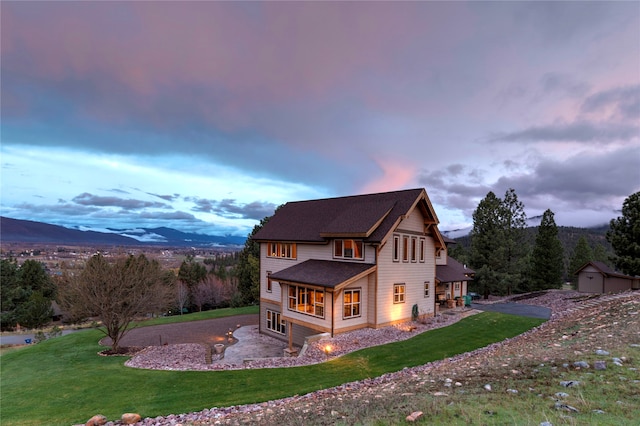 back house at dusk featuring a shed, a yard, and a mountain view